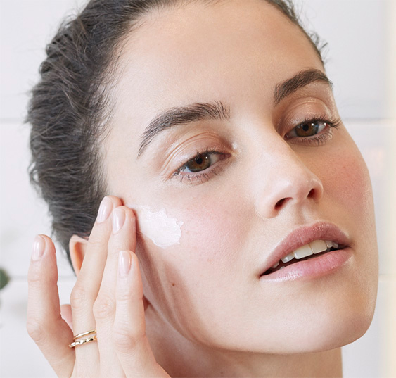 Woman moisturizing her face