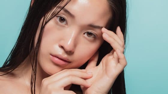 A close up of a woman with a tilted head and hands in the frame