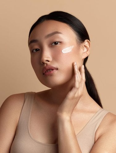 A woman with a stroke of moisturiser on her cheekbone